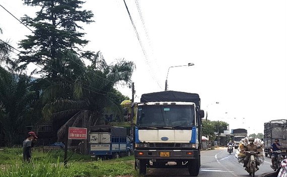 Tài xế (mũ đỏ) xuống xe vì không chịu nổi mùi cay nồng. Trong khi đó, người đi đường phải bịt mũi khi đi qua xe tải