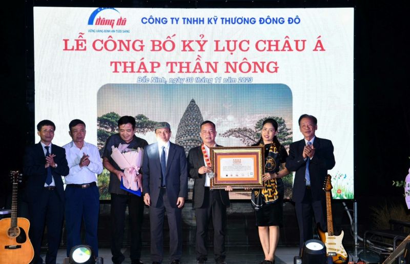 Vợ chồng ông Trần Văn Toản - Chủ tịch HĐTV - Tổng Giám đốc Công ty TNHH Kỹ thương Đông Đô nhận kỷ lục Châu Á cho công trình bảo tháp Thần Nông - tòa tháp hình hạt lúa mang tính nghệ thuật và là biểu trưng của nền văn minh lúa nước ở Việt Nam.