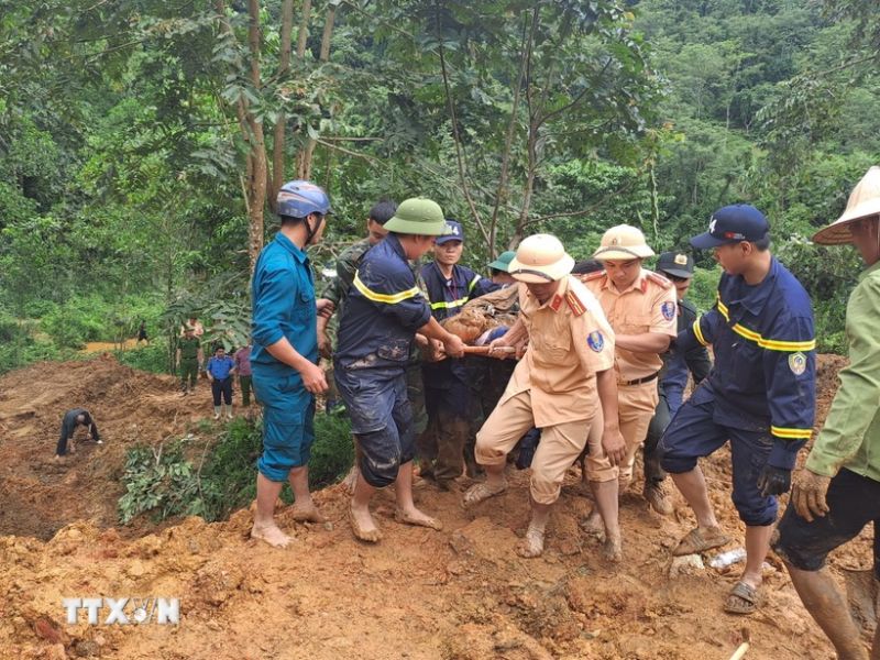 Các lực lượng tìm kiếm đưa thi thể nạn nhân bị vùi lấp ra khỏi khu vực sạt lở. (Ảnh: Đức Thọ/TTXVN)