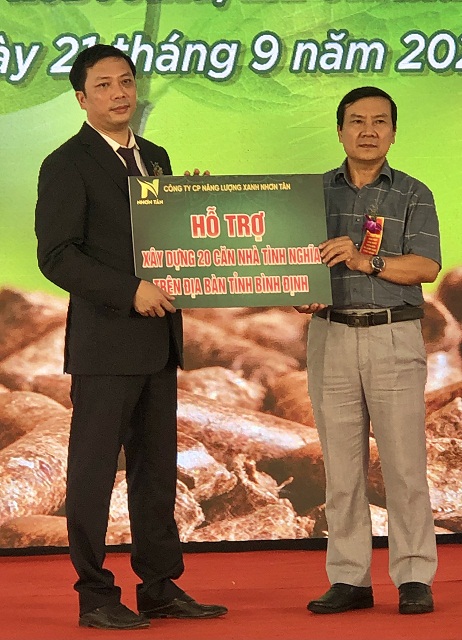 Ông Phạm Văn Nam (bên phải) nhận 200 triệu đồng và bảng “Hỗ trợ xây dựng 20 căn nhà tình nghĩ” từ lãnh đạo Công ty CP năng lượng xanh Nhơn Tân.