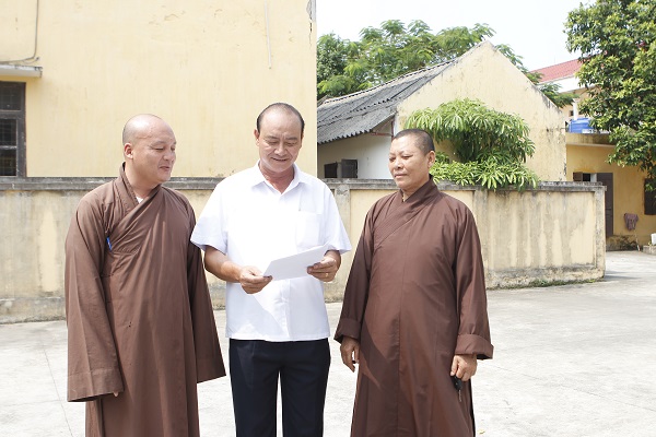 Ông Doãn Đình Triều (người đứng giữa) trao đổi kinh nghiệm tuyên truyền với các chức sức tôn giáo Phậ giáo về vận động tín đồ, nhân dân hưởng ứng phong trào Xây dựng Chùa tinh tiến
