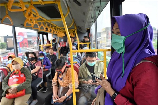 Hành khách đeo khẩu trang trên xe buýt tại Jakarta, Indonesia, ngày 18/3 (Ảnh: AFP/TTXVN)