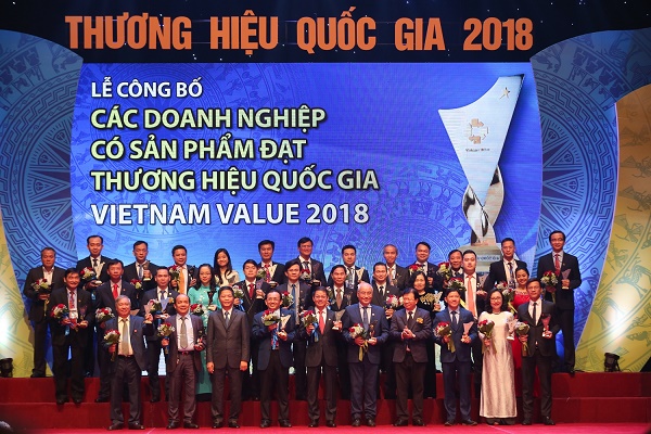 Phó Thủ tướng Trịnh Đình Dũng và Bộ trưởng Bộ Công Thương Trần Tuấn Anh chụp ảnh lưu niệm cùng đại diện các doanh nghiệp có sản phẩm được công nhận Thương hiệu Quốc gia năm 2018