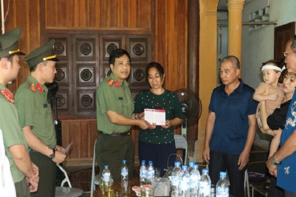 Đại tá Hồ Văn Tứ, Phó Giám đốc Công an tỉnh Nghệ An trao tặng sổ tiết kiệm cho bố, mẹ Đại úy Sầm Quốc Nghĩa. Ảnh: Đức Vũ