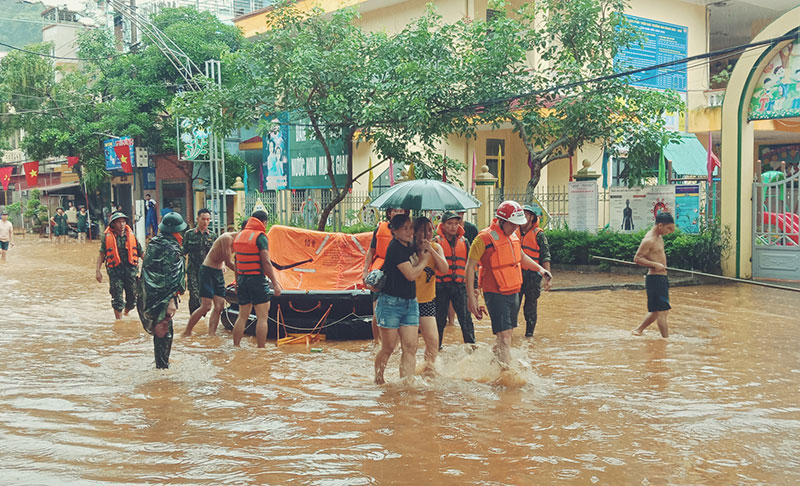 Lực lượng chức năng hỗ trợ người dân từ vùng ngập úng đến nơi an toàn