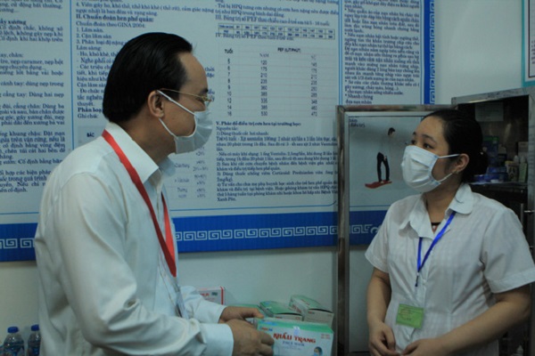 Bộ trưởng Bộ GD-ĐT Phùng Xuân Nhạ trao đổi với nhân viên y tế về các trang thiết bị dự phòng cho kỳ thi tại Trường THCS Nam Từ Liêm (Hà Nội) - Ảnh: VĨNH HÀ