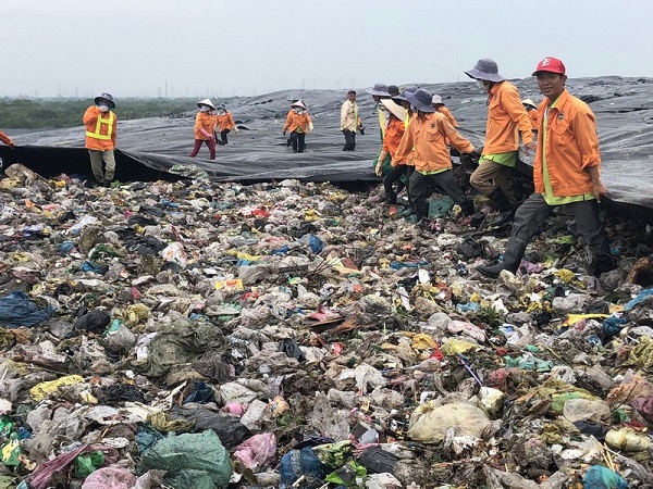 Công nhân kéo bạt che phủ bãi rác nhằm giảm thiểu phát tán mùi hôi ra cộng đồng.