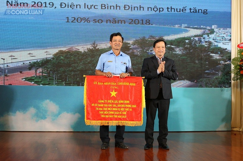 PCT UBND tỉnh Bình Định Nguyễn Tuấn Thanh (bên phải) trao cờ thi đua của UBND tỉnh cho Công ty Điện lực