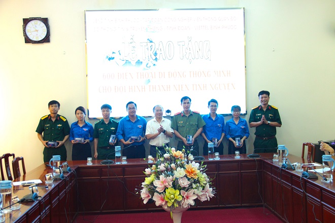 Ông Nguyễn Minh Quang - Phó Giám đốc phụ trách Sở TT-TT (bên trái, ngoài cùng) và ông Chu Hồng Quảng - Giám đốc Viettel Bình Phước (bên phải, ngoài cùng) trao tặng điện thoại thông minh cho đại diện các đội hình thanh niên tình nguyện