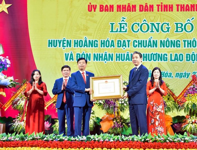 Thừa ủy quyền của Thủ tướng Chính phủ, đồng chí Lê Đức Giang, Phó Chủ tịch UBND tỉnh trao Quyết định công nhận huyện Hoằng Hóa đạt chuẩn NTM năm 2019. (Ảnh: Hoàng Đông)
