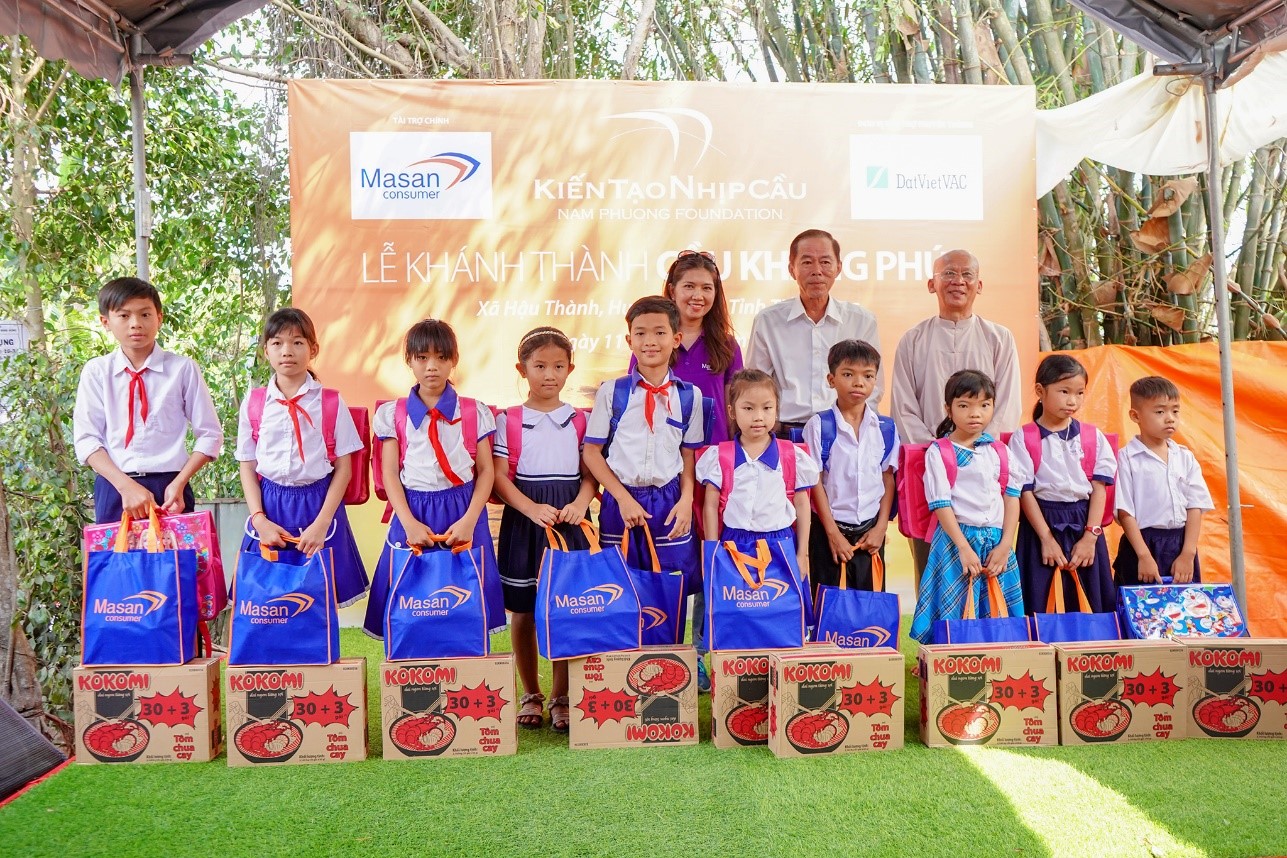 Nhân viên công ty Cổ phần Hàng tiêu dùng Masan trao quà cho các em học sinh và bà con