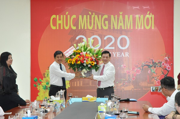 Ông Nguyễn Lợi (phải) thay mặt CB-CCVC ngành ngân hàng nhận hoa và quà chúc mừng năm mới của Phó Chủ tịch Tỉnh Nguyễn Thành Long
