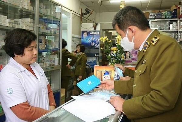 Cán bộ quản lý thị trường kiểm tra giá bán khẩu trang y tế tại một nhà thuốc ở Hà Nội