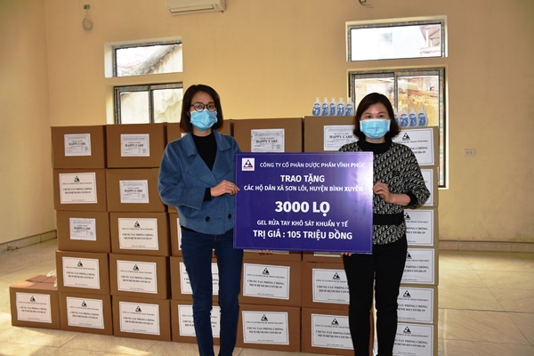 Bà Vũ Thị Bình, Giám đốc Tài chính Công ty Cổ phần dược phẩm Vĩnh Phúc trao tặng nước sát trùng và găng tay y tế cho đại diện UBND huyện Bình Xuyên.