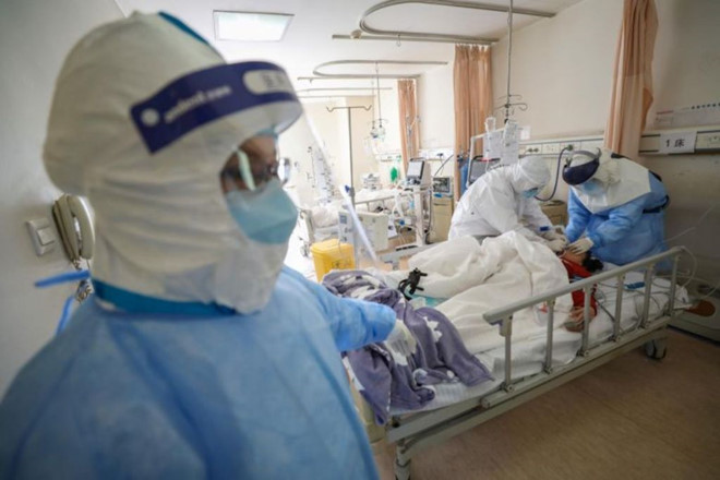 Các y bác sĩ đang điều trị một bệnh nhân nhiễm Covid-19 ở khu vực cách ly (Ảnh Reuters)