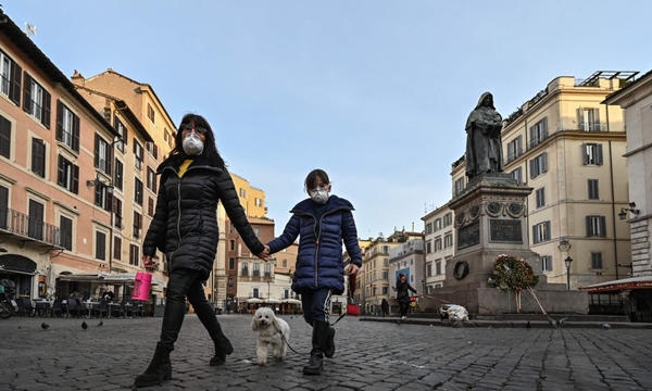 Mẹ dắt tay con gái nhỏ và chó cưng đi dạo ở quảng trường Campo Dei Fiori vắng vẻ tại trung tâm Roma hôm 10/3 (Ảnh: Getty Images)