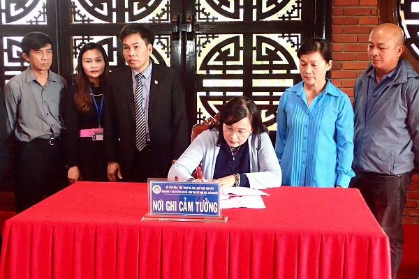 Chủ tịch H&ocirc;̣i NSNAVN Tr&acirc;̀n Thị Thu Đ&ocirc;ng vi&ecirc;́t lưu ni&ecirc;̣m vào s&ocirc;̉ của nhà tưởng ni&ecirc;̣m Chủ tịch H&ocirc;̀ Chí Minh