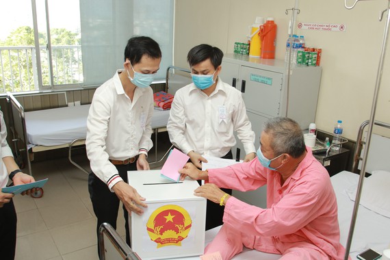 Thạc sĩ Lê Minh Hiển cùng nhân viên UBND Phường 12, Quận 5 mang thùng phiếu đến tận giường bệnh để bệnh nhân thực hiện quyền bầu cử