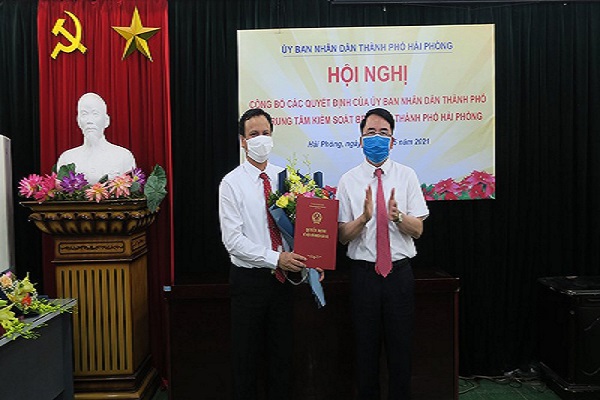 Ông Lê Khắc Nam, Phó chủ tịch UBND TP Hải Phòng (bên phải), trao quyết định và tặng hoa chúc mừng ông Nguyễn Quang Chính, giám đốc đầu tiên của CDC Hải Phòng. Ảnh: H.P.