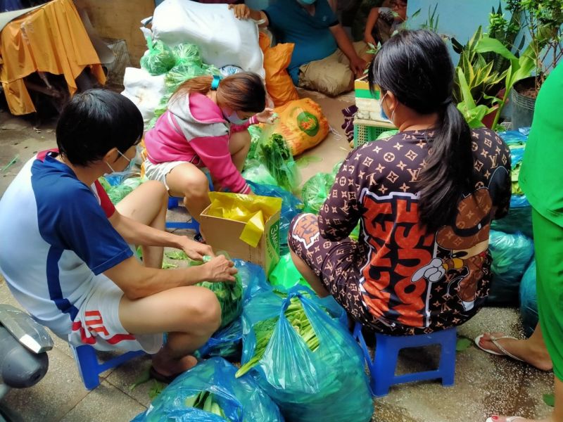 Một số người dân quận 8 (TP Hồ Chí Minh) cùng nhóm của anh Đậu Viết Năng xếp rau xanh từ Bình Phước thành những suất quà đượm tình để gửi đến các hộ gia đình khó khăn
