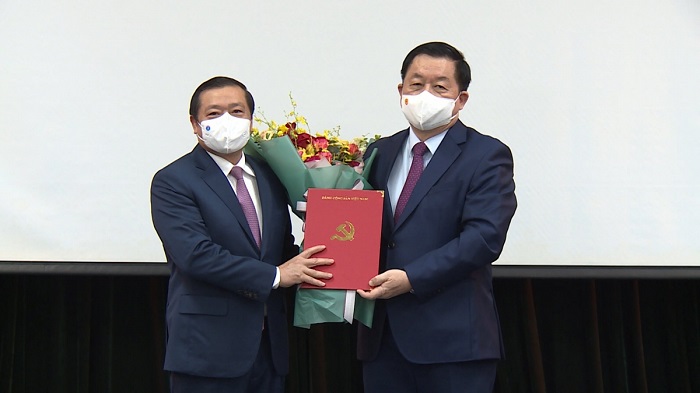Trưởng Ban Tuyên giáo Trung ương Nguyễn Trọng Nghĩa trao quyết định và tặng hoa chúc mừng ông Lại Xuân Môn