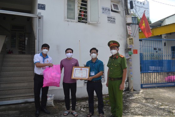 Đại diện Công an TP Thủ Đức và UBND phường Linh Trung trao tặng giấy khen cho người dân vì đã tự nguyện nhường phần hỗ trợ của gia đình mình cho người khó khăn hơn