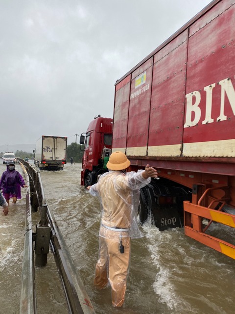 Lực lượng CSGT hướng dẫn xe ô tô qua vùng ngập trên Quốc lộ 1A, thuộc huyện Phú Lộc, TT Huế