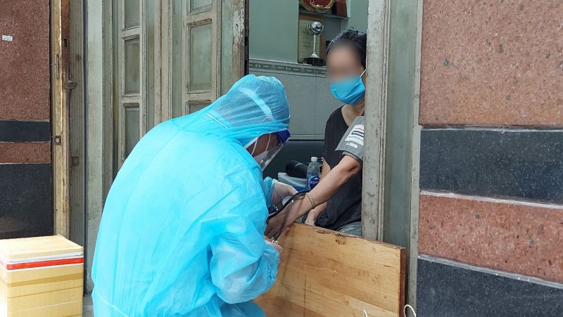 Trong hình là Nhân viên y tế tại Trạm Y tế phường 8, quận 11, TP. Hồ Chí Minh thăm khám cho F0 tại nhà.