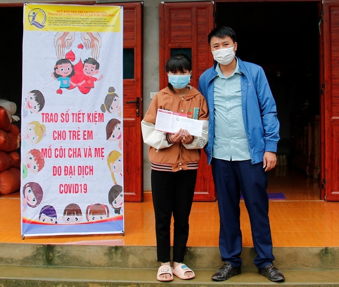 Ông Lại Thế Quảng, Giám đốc Quỹ Bảo trợ trẻ em tỉnh trao sổ tiết kiệm và tiền mặt cho cháu Trương Tường Vi ở xã Thạch Tượng, huyện Thạch Thành, có mẹ bị nhiễm COVID-19