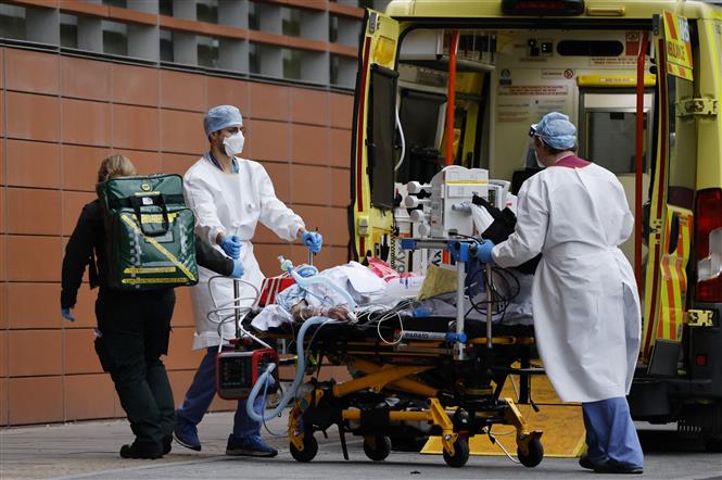 Nhân viên y tế chuyển bệnh nhân nhiễm Covid-19 tới bệnh viện ở London, Anh (Ảnh: AFP/TTXVN)