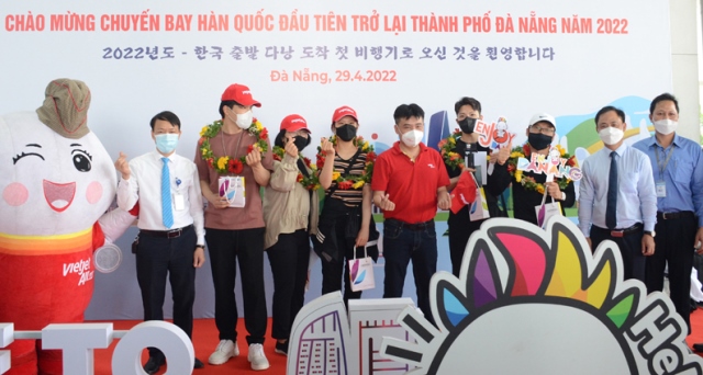 Phó Giám đốc Sở Du lịch Nguyễn Xuân Bình (thứ 3, từ phải sang) cùng đại diện hãng hàng không tặng hoa, chúc mừng những vị khách trên chuyến bay từ Hàn Quốc đến Đà Nẵng