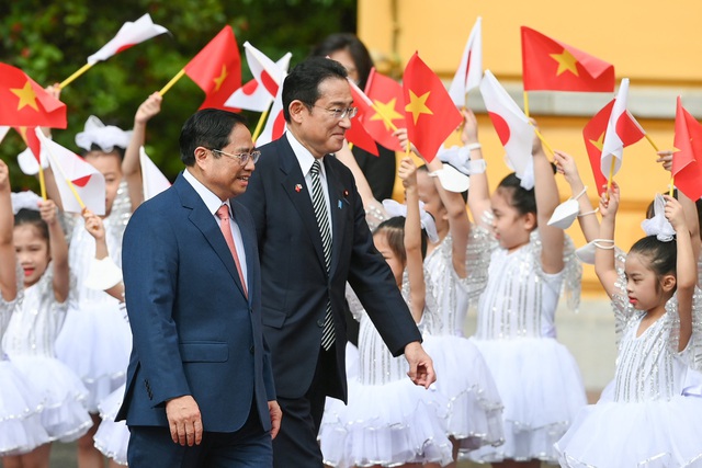 Thủ tướng Phạm Minh Chính mời Thủ tướng Kishida Fumio bước trên thảm đỏ trong tiếng vẫy chào của các em học sinh. Ảnh VGP/Nhật Bắc