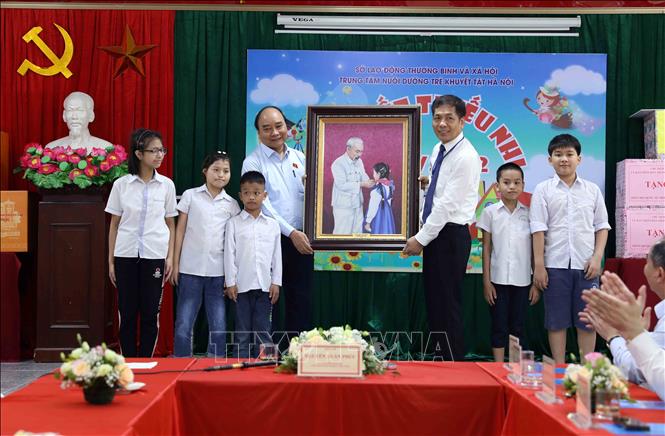 Chủ tịch nước Nguyễn Xuân Phúc tặng bức tranh Chủ tịch Hồ Chí Minh với thiếu nhi cho Trung tâm Nuôi dưỡng trẻ khuyết tật Hà Nội (Ảnh TTXVN)