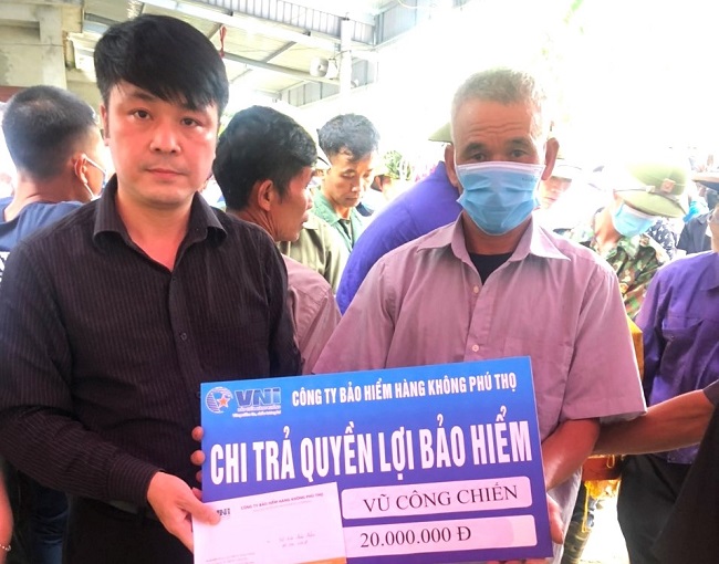 Đại diện VNI Phú Thọ (bên trái) chi trả 20 triệu đồng bồi thường bảo hiểm cho gia đình em Vũ Công Chiến, học sinh lớp 10A9 trường THPT Nguyễn Bỉnh Khiểm. huyện Hạ Hòa