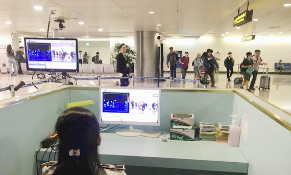 Nhân viên sân bay Tân Sơn Nhất kiểm tra màn hình hiển thị máy quét thân nhiệt đối với hành khách quốc tế đến Việt Nam