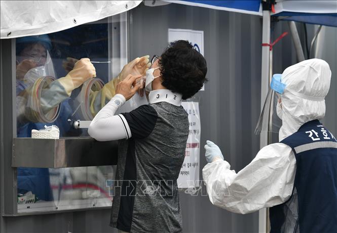 Nhân viên y tế lấy mẫu dịch xét nghiệm Covid-19 cho người dân tại Seoul, Hàn Quốc (Ảnh AFP/TTXVN)