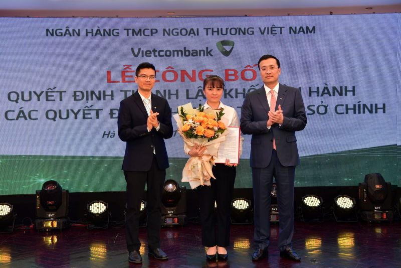 Ông Phạm Quang Dũng - Chủ tịch HĐQT (bên phải) trao quyết định và ông Trần Thanh Nam - Giám đốc Khối Vận hành (bên trái) tặng hoa chúc mừng bà Thái Thị Thu Hằng - tân Phó trưởng phòng phụ trách Phòng Quản lý chất lượng - Trụ sở chính Vietcombank