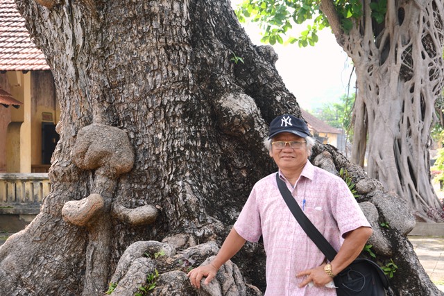 Nhà báo Trần Đinh Quang dưới gốc cây bàng di sản hàng trăm năm tuổi ở Côn Đảo .