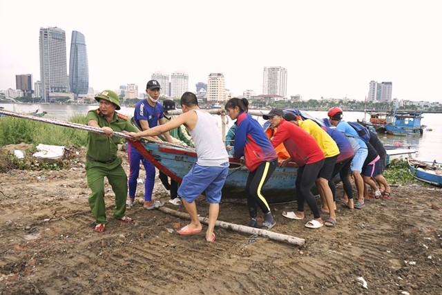 Lực lượng Công an TP. Đà Nẵng cùng người dân hỗ trợ đưa phương tiện lên bờ tránh bão