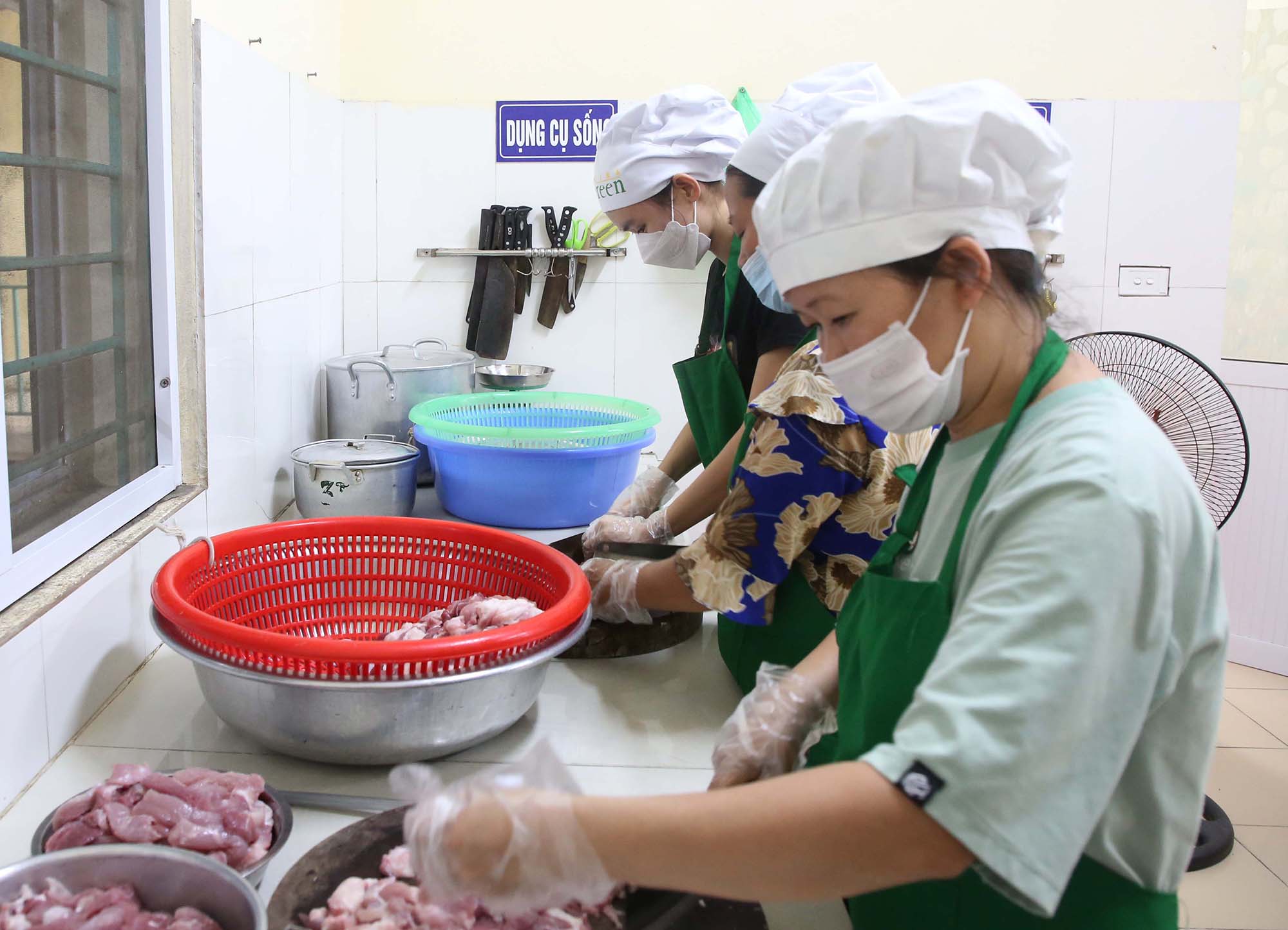Nhân viên bếp Trường Mầm non Kinh Bắc trang bị đầy đủ đồ bảo hộ sơ chế thực phẩm, chuẩn bị bữa ăn cho học sinh.