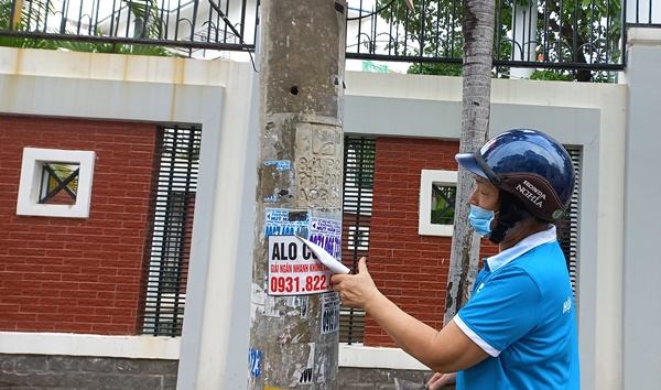 Các hội viên đoàn thể khu phố phải vất vả bóc, gỡ những mảnh giấy quảng cáo nhem nhuốc trên tường, các cột đèn