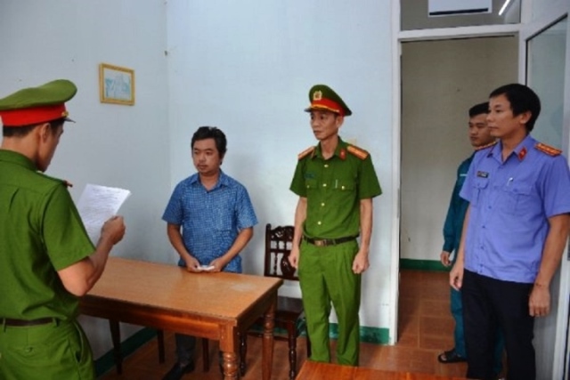 Lực lượng chức năng đọc quyết định khởi tố, bắt tạm giam Nguyễn Hoàng Minh. (Ảnh: C.A)
