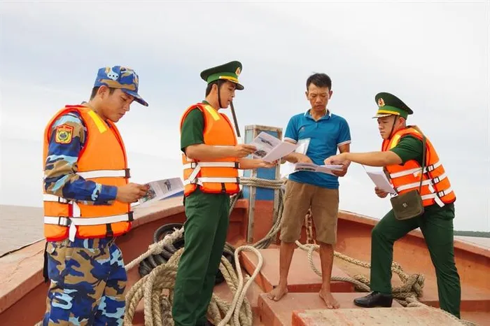 Cán bộ Đồn Biên phòng Trung Bình và Hải đội 2, BĐBP Sóc Trăng cấp phát tài liệu tuyên truyền về chống khai thác hải sản