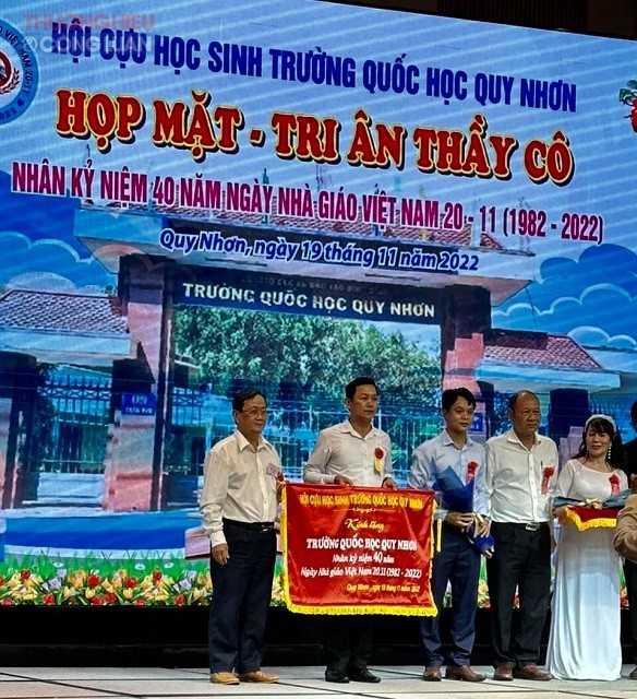 Đại diện Hội Cựu học sinh Trường Quốc học Quy trao tặng Trường Quốc học Quy Nhơn Cờ lưu niệm nh&acirc;n kỷ niệm 40 năm Ng&agrave;y Nh&agrave; gi&aacute;o Việt Nam.