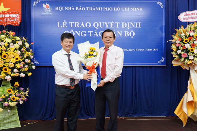 Nhà báo Nguyễn Tấn Phong (phải) nhận hoa và quyết định giữ chức Chủ tịch Hội Nhà báo TP.HCM