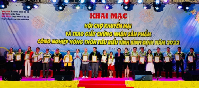 - Các ông, bà: Nguyễn Tuấn Thanh (thứ 09 từ phải qua), Nguyễn Thị Phong Vũ (thư 08từ trái qua) trao Giấy chứng nhận “Sản phẩm CNNT tiêu biểu tỉnh Bình Định năm 2022” cho các DN, HTX, cơ sở sản xuất…