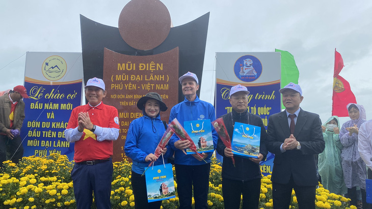 Nguyên Phó thủ tướng thường trực Trương Hòa Bình (bìa trái) và Phó chủ tịch UBND tỉnh Phú Yên Đào Mỹ (bìa phải) tặng hoa, quà cho các du khách tham gia chào cờ Tổ quốc tại danh thắng quốc gia Mũi Điện sáng 1-1-2023 - Ảnh: TƯỜNG NGUYÊN