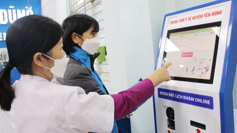 Nhân viên Trung tâm Y tế huyện Yên Dũng hướng dẫn người dân lấy số khám bệnh tự động