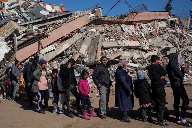 Người dân Thổ Nhĩ Kỳ xếp hàng bên đống đổ nát của trận động đất để nhận thực phẩm miễn phí. (Ảnh: Reuters)