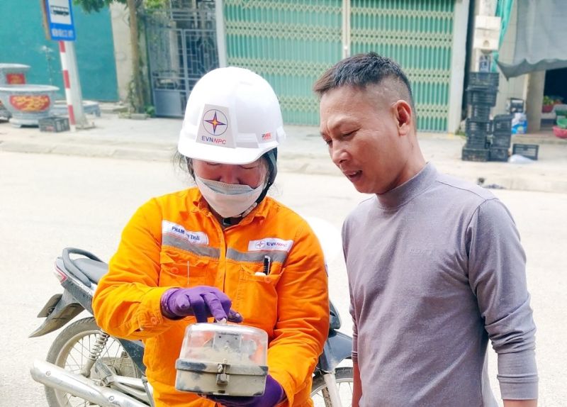 Công nhân Điện lực khu vực Bỉm Sơn - Hà Trung (PC Thanh Hóa) hướng dẫn khách hàng xem và chốt chỉ số trên công tơ cơ khí cũ trước khi thay thế bằng lắp đặt công tơ điện tử